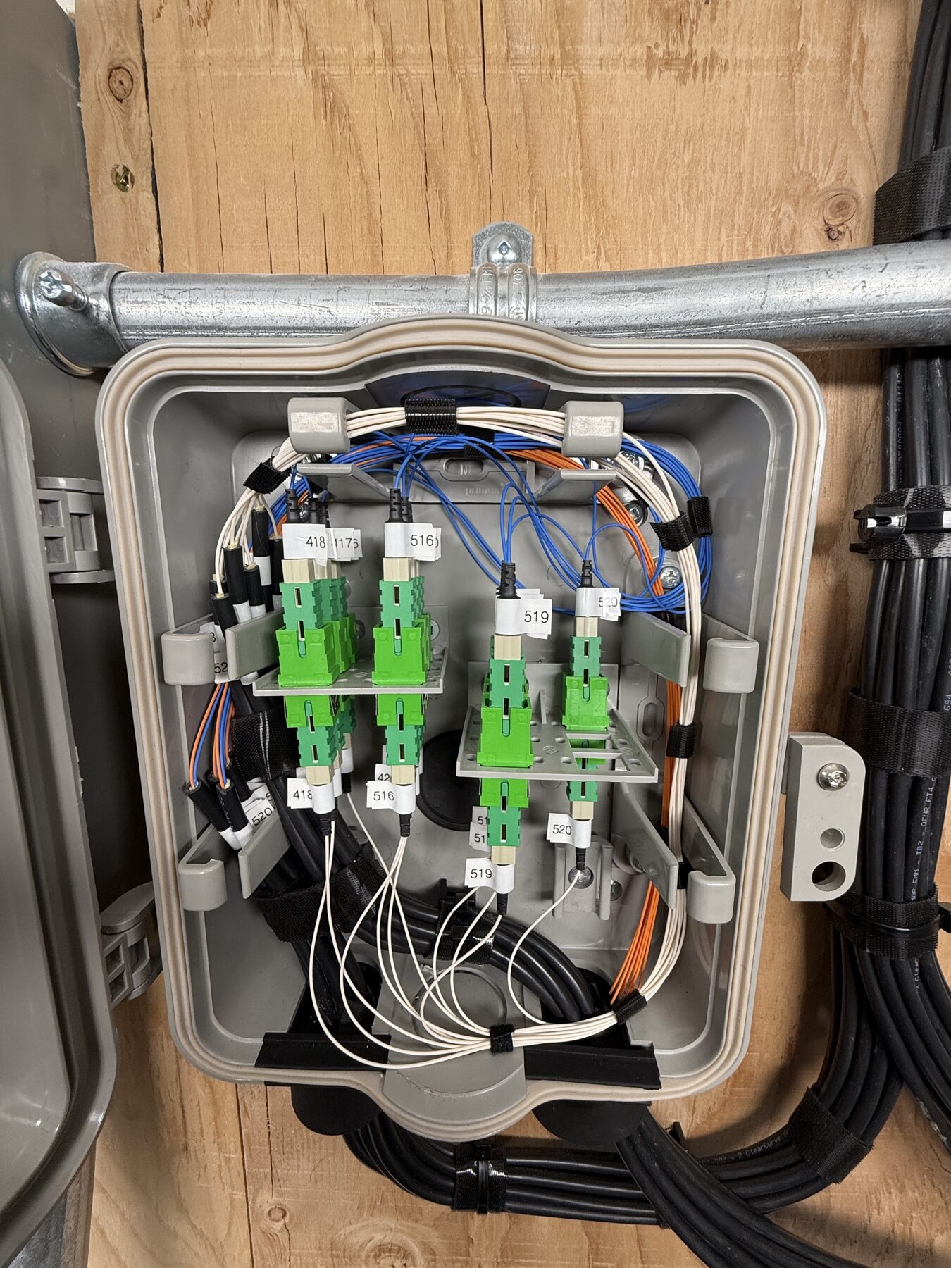 Open splice enclosure with green fiber adapters and labeled fiber leads