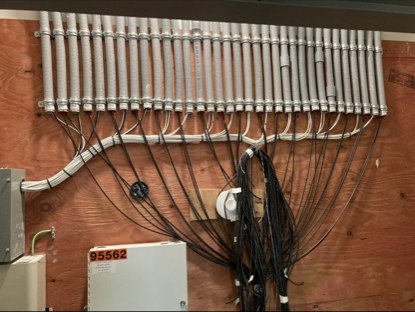 Metal conduit bank with individually routed black cabling and a service cabinet