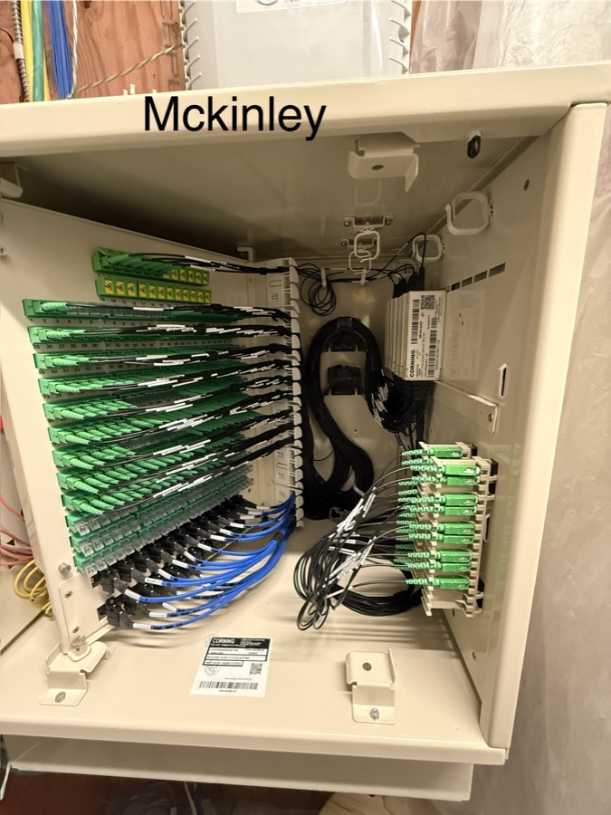 Open distribution cabinet with rows of labeled green fiber adapters