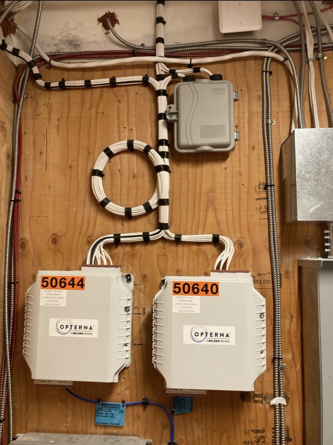 Two wall-mounted fiber service enclosures with dressed white cabling and a service loop