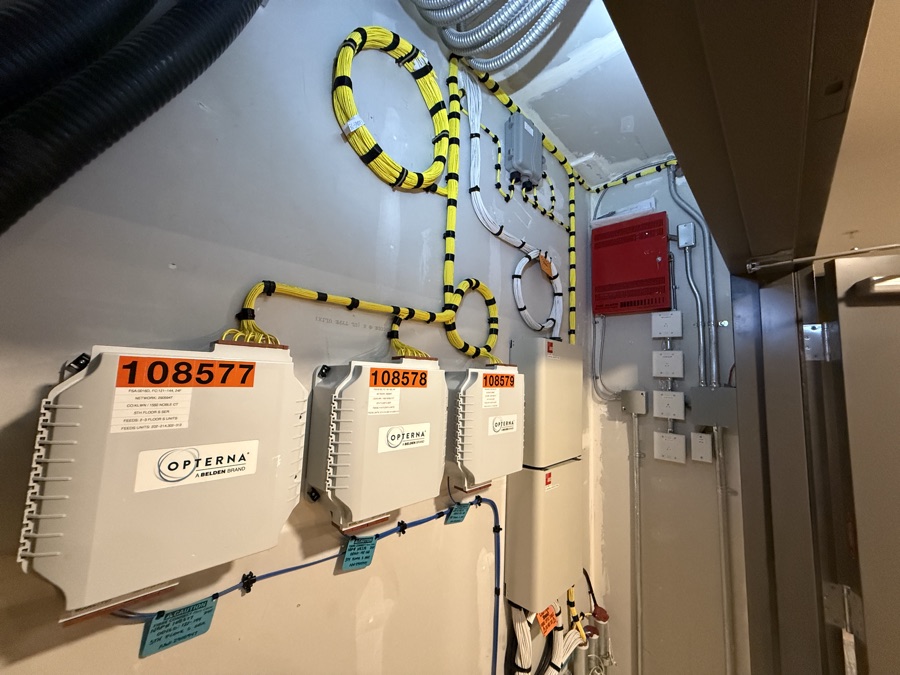 Wall-mounted fiber enclosures linked by neatly routed striped conduits