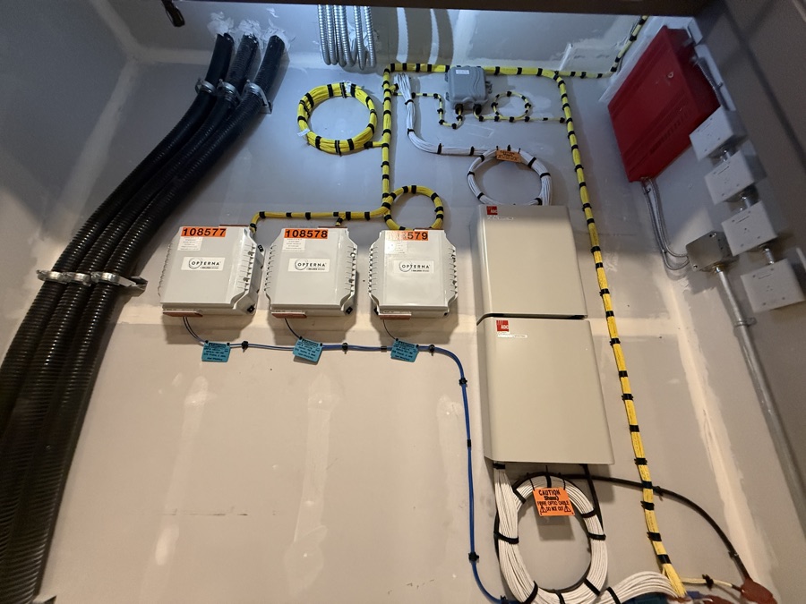 Communications backboard with mounted service boxes and neatly looped striped cabling