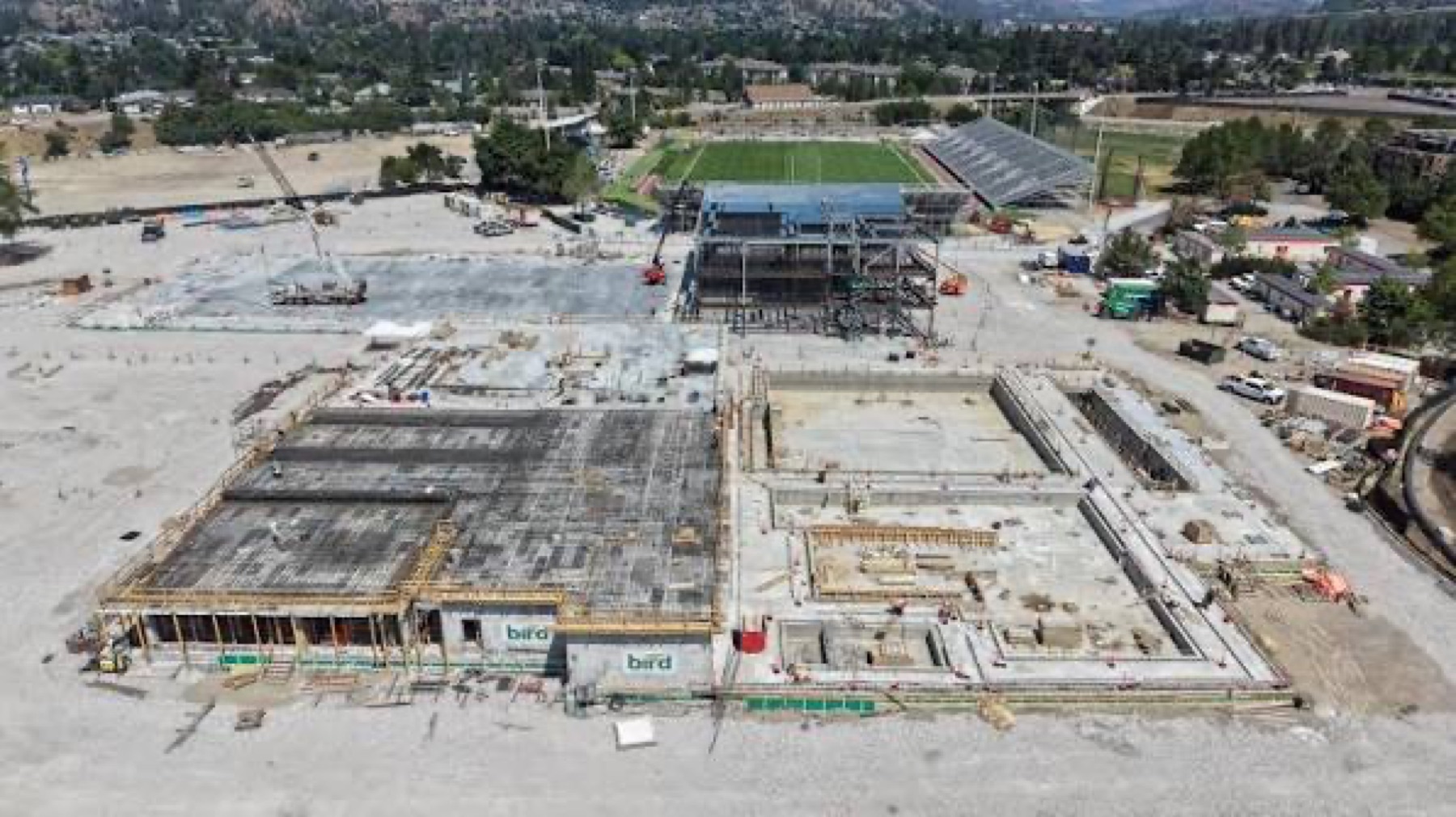 Aerial view of concrete foundations and steel framing across an active recreation-centre construction site