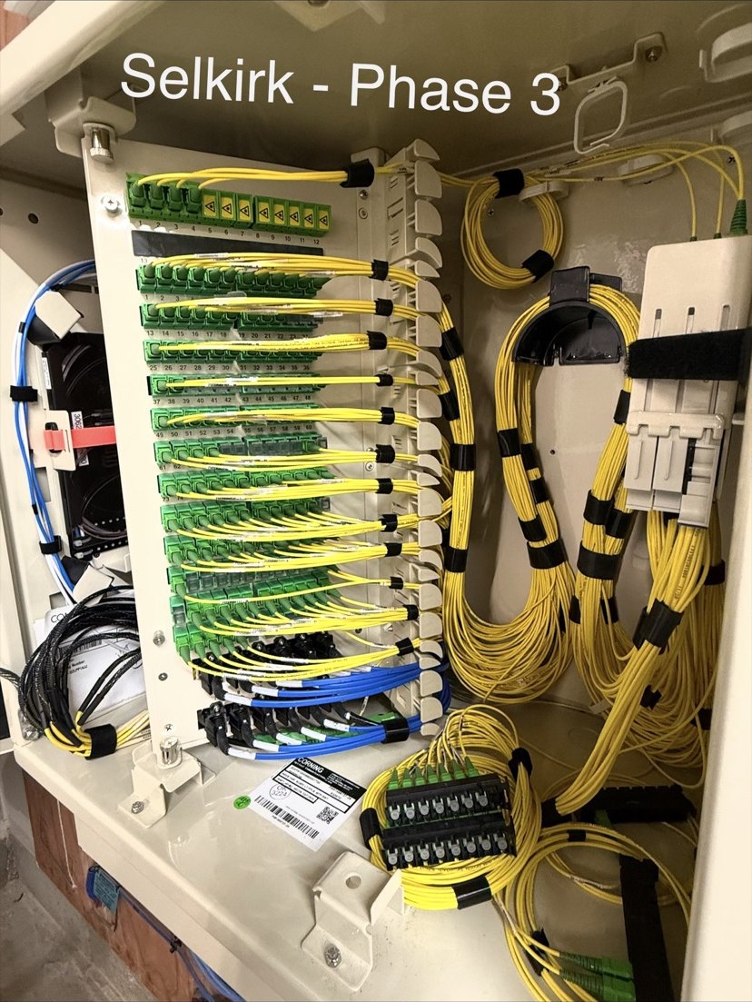 Open fiber distribution cabinet with rows of green adapters and routed yellow patch fibers