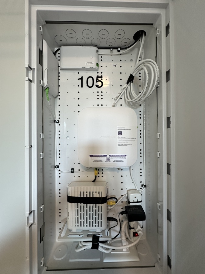 Residential communications cabinet with coiled service cable and terminations